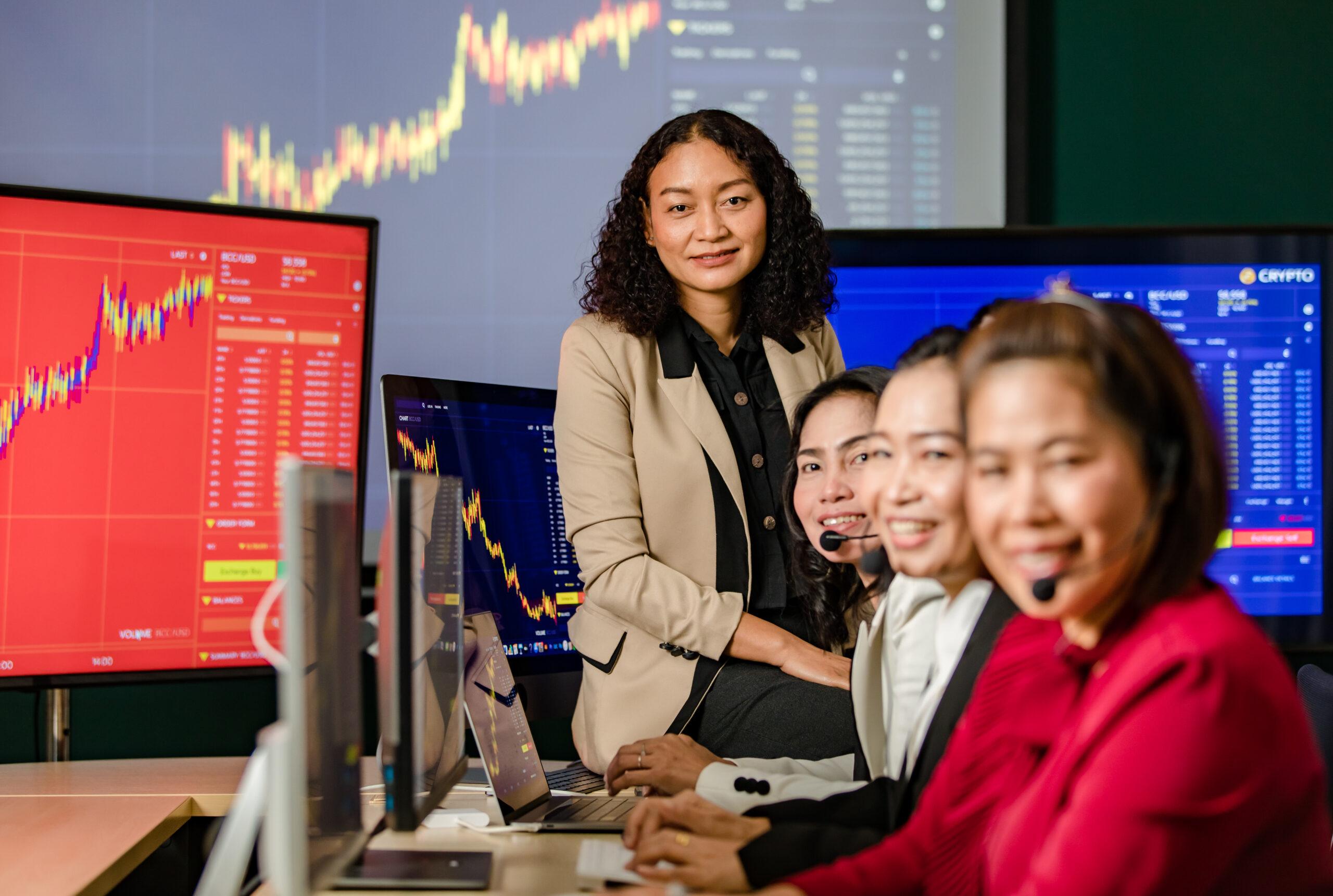 asian female professional stock exchange manager sit desk smile front monitor look camera scaled