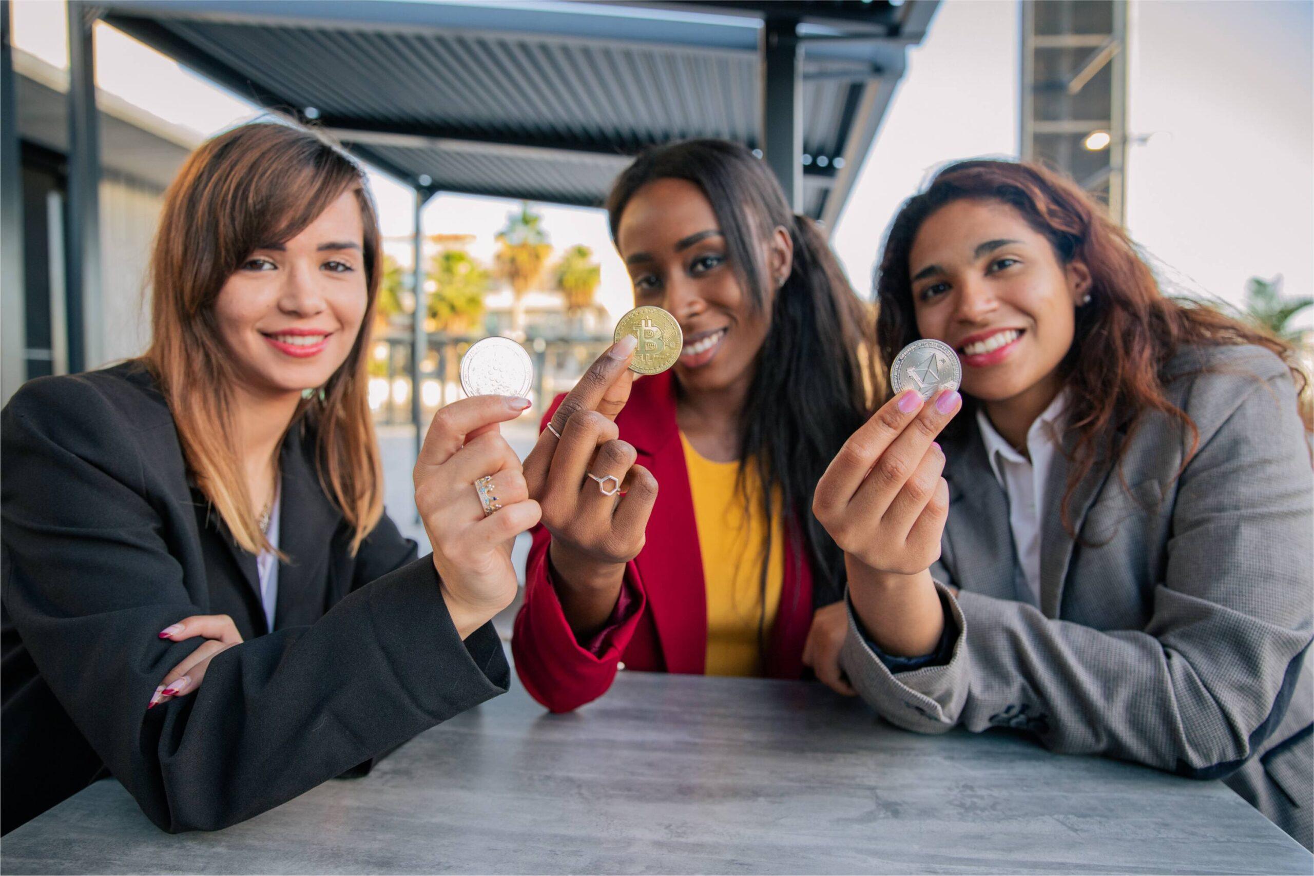 three women hold three crypto coins in their hands 2023 11 27 04 52 00 utc 1 scaled